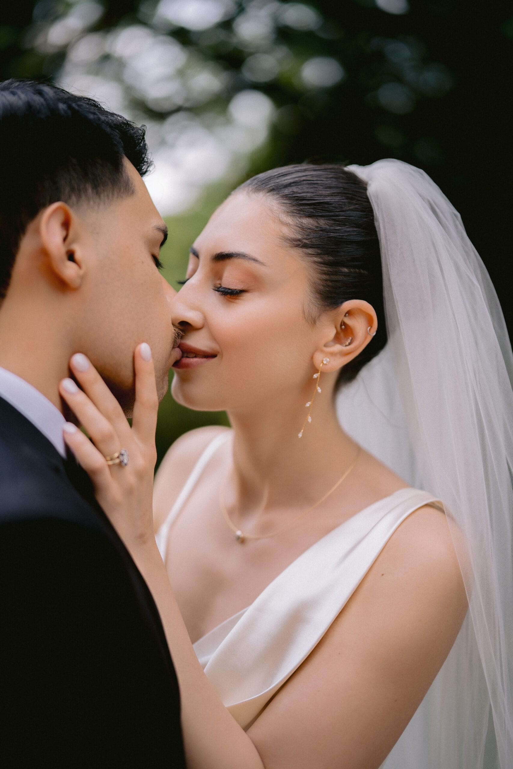 Close-up of a bride and groom about to kiss outdoors.