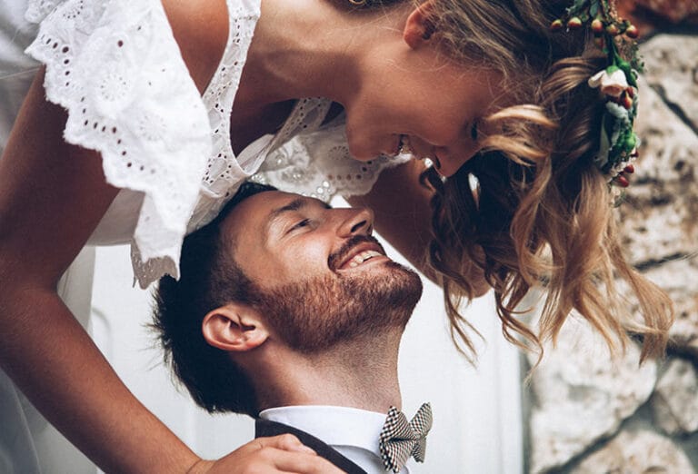 Smiling couple in wedding attire embracing closely.